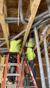 Installers weaving duct through the structure